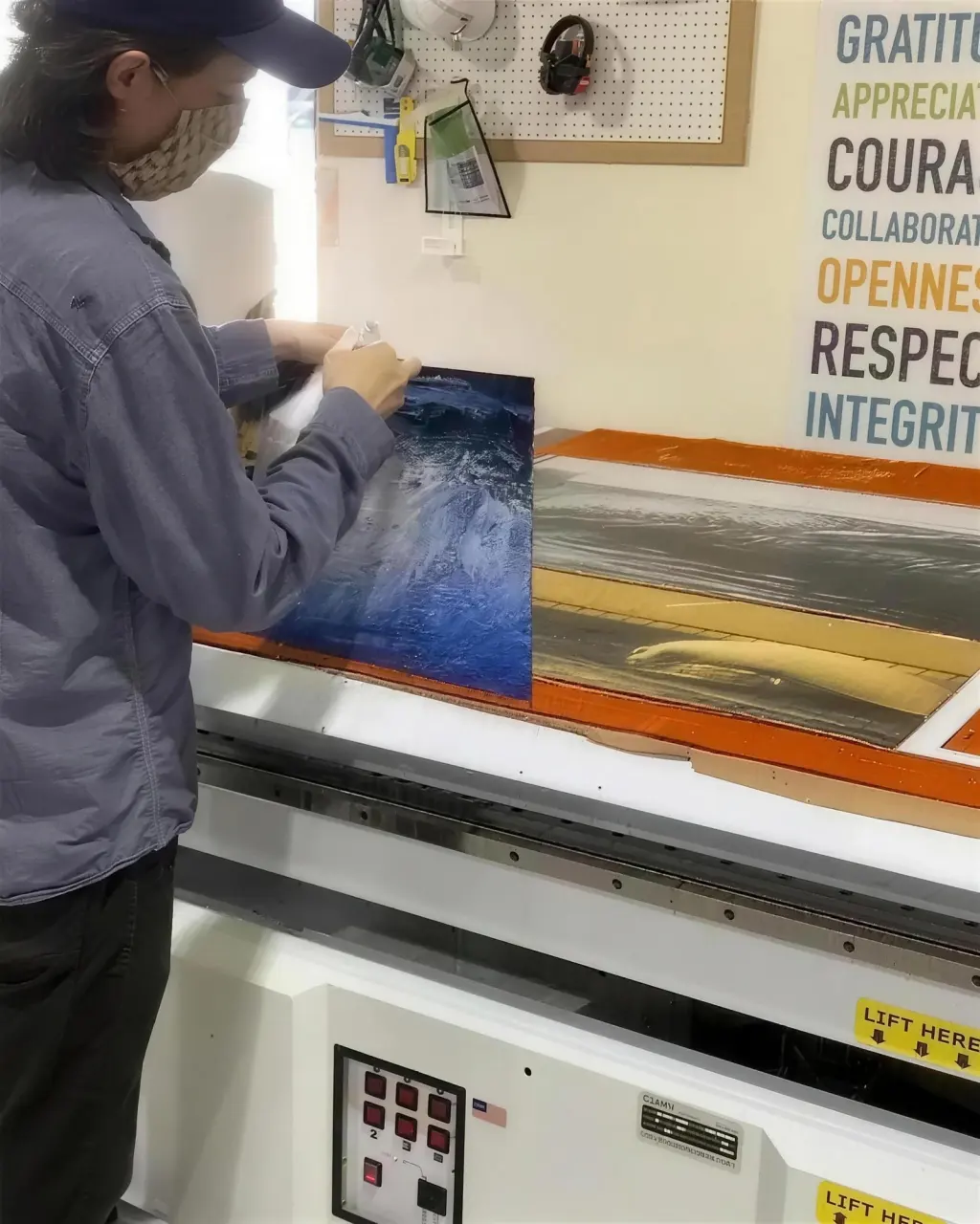 A printer loading artwork onto the flatbed in the print lab