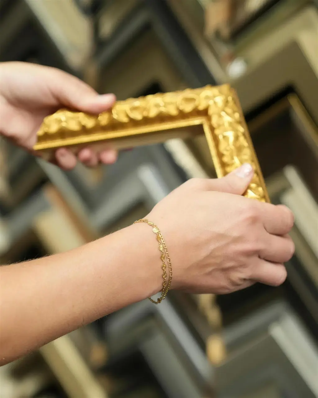 A framer holding a carved gilt corner sample in front of the moulding wall