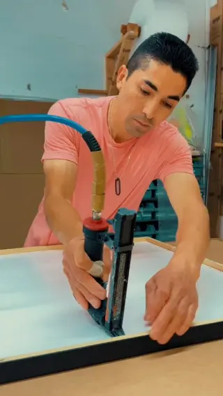 A framer in a pink T-shirt driving points into a black frame at the fitting bench