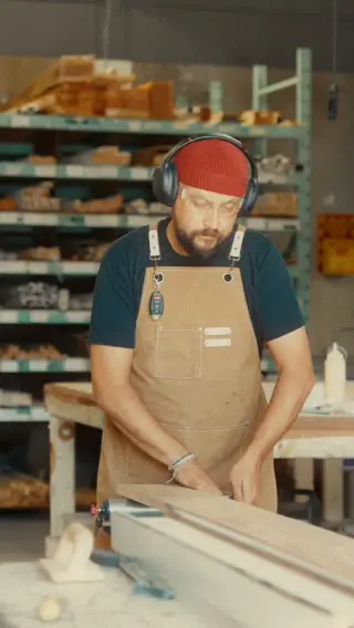 A framer in ear protection working at the bench in the wood shop