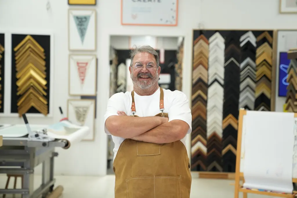 A Best Framing framer, arms crossed, in front of a display of moulding corners