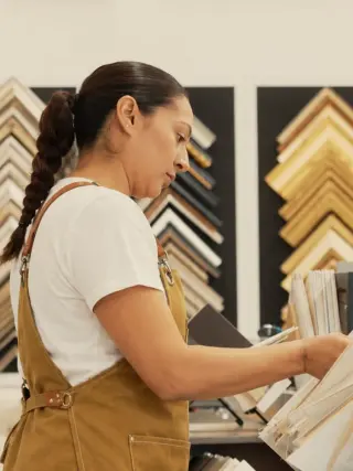 Aylin choosing mat samples at the design counter, moulding corner samples on the wall behind her