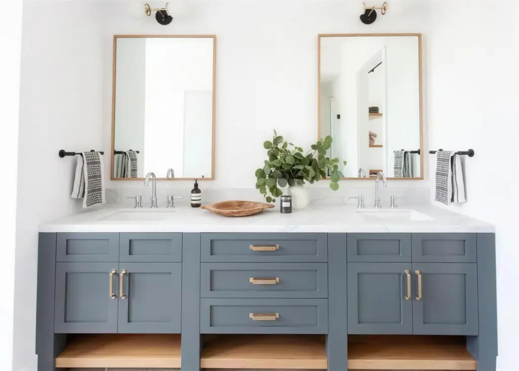 two oak framed mirrors over a slate blue vanity with brass sconces