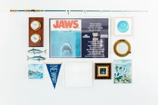 Flat-lay coastal gallery wall - Jaws quad poster, porthole mirror, Newport pennant