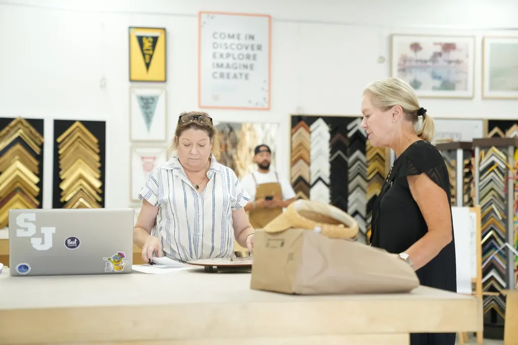Two customers working through an order with a designer at the counter