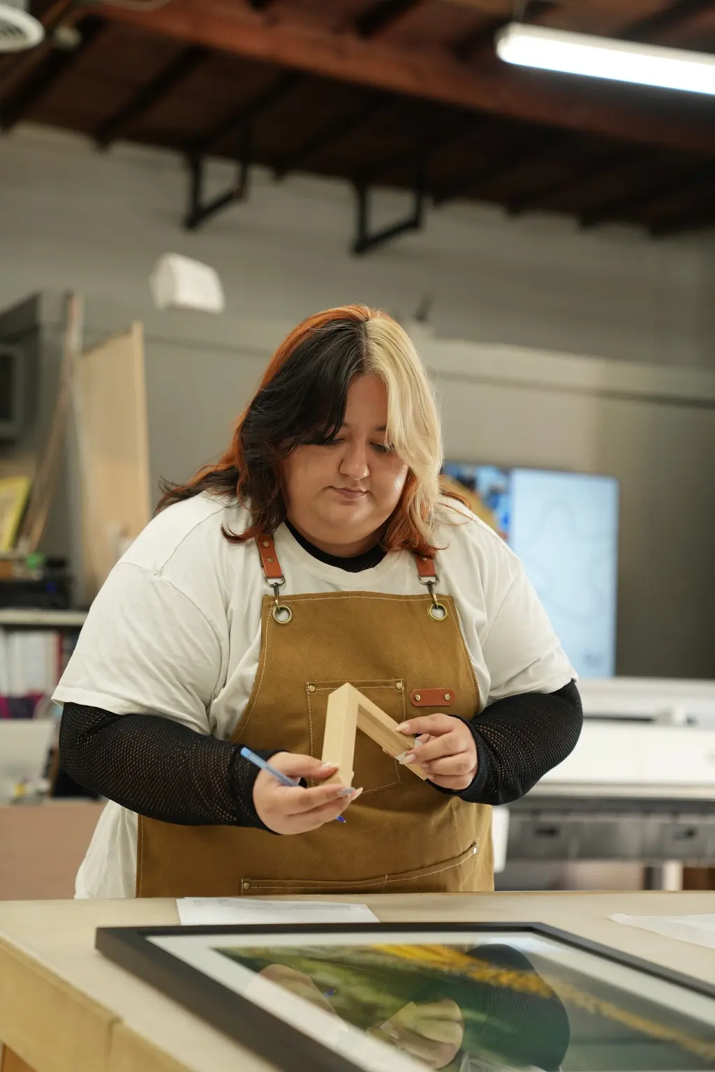 A designer holding a corner sample against a framed print at the design table