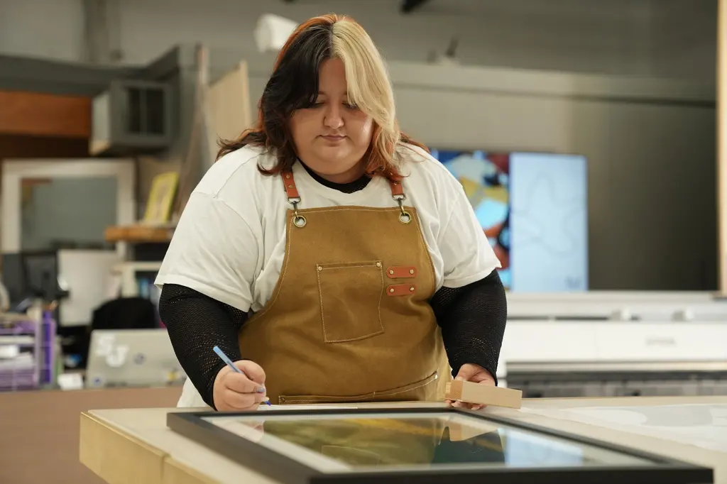 A designer marking up a framed print at the design table