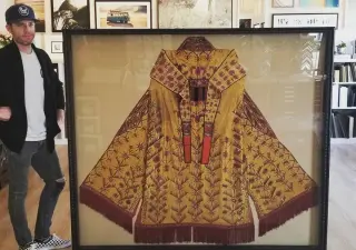 An antique gold kimono framed in a deep black moulding, standing in the Best Framing showroom