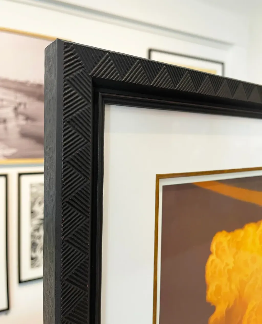 Top-corner macro of a carved herringbone black moulding with gold fillet