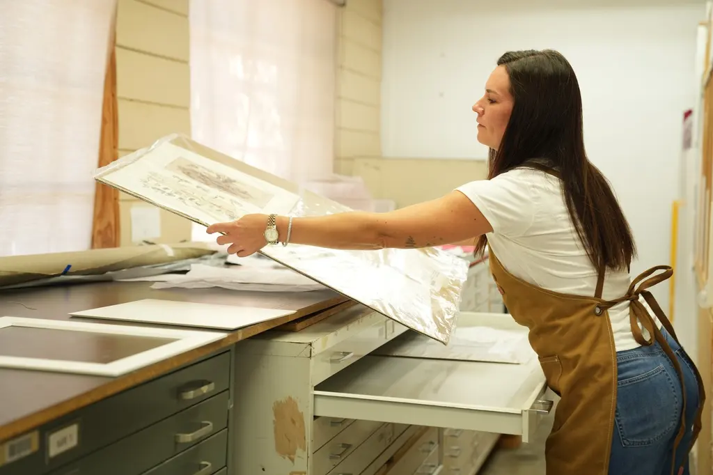 A designer lifting a mat board out of the flat-file drawers in the mat room