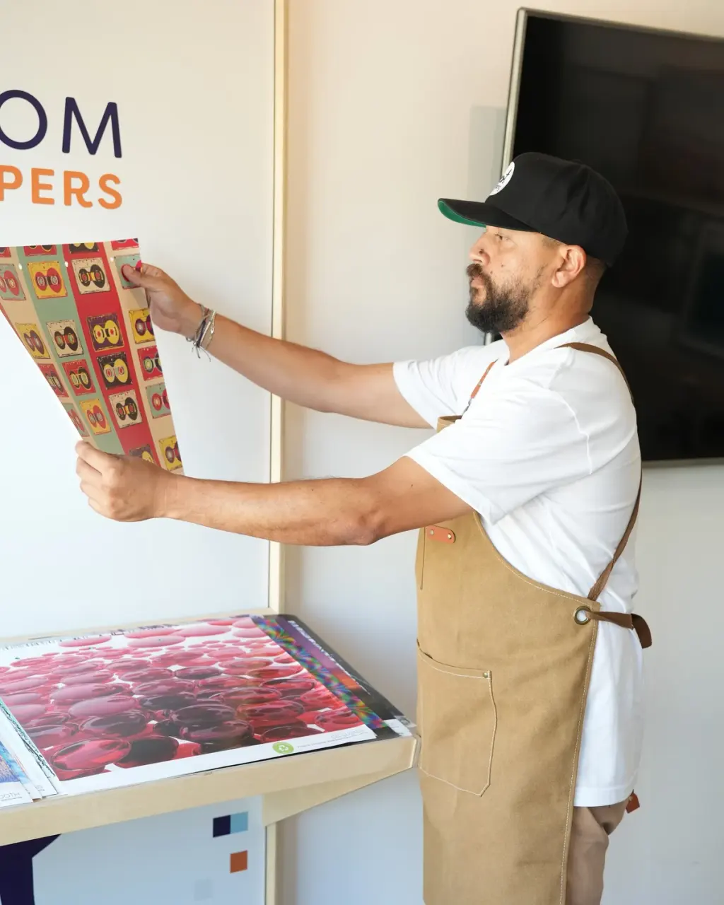 Medi holding a printed wallpaper sample up to the light in the print area