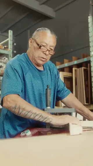 German, the chop-and-join specialist, working at the bench with lengths of moulding racked behind him