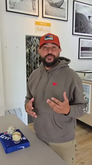 A Best Framing designer talking a project through in the showroom, a rack of moulding corner samples in the doorway behind him