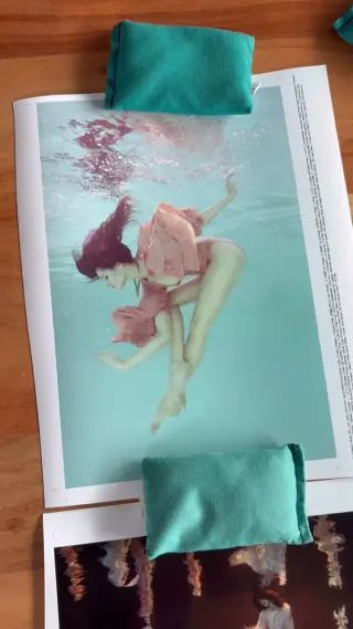 Proof prints of an underwater photograph laid out on the wooden bench in the print lab, fabric weight bags holding the sheets flat