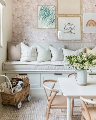 A children’s nook with a four-piece gallery wall of watercolor leaves, a calligraphy print and a rainbow above a window bench