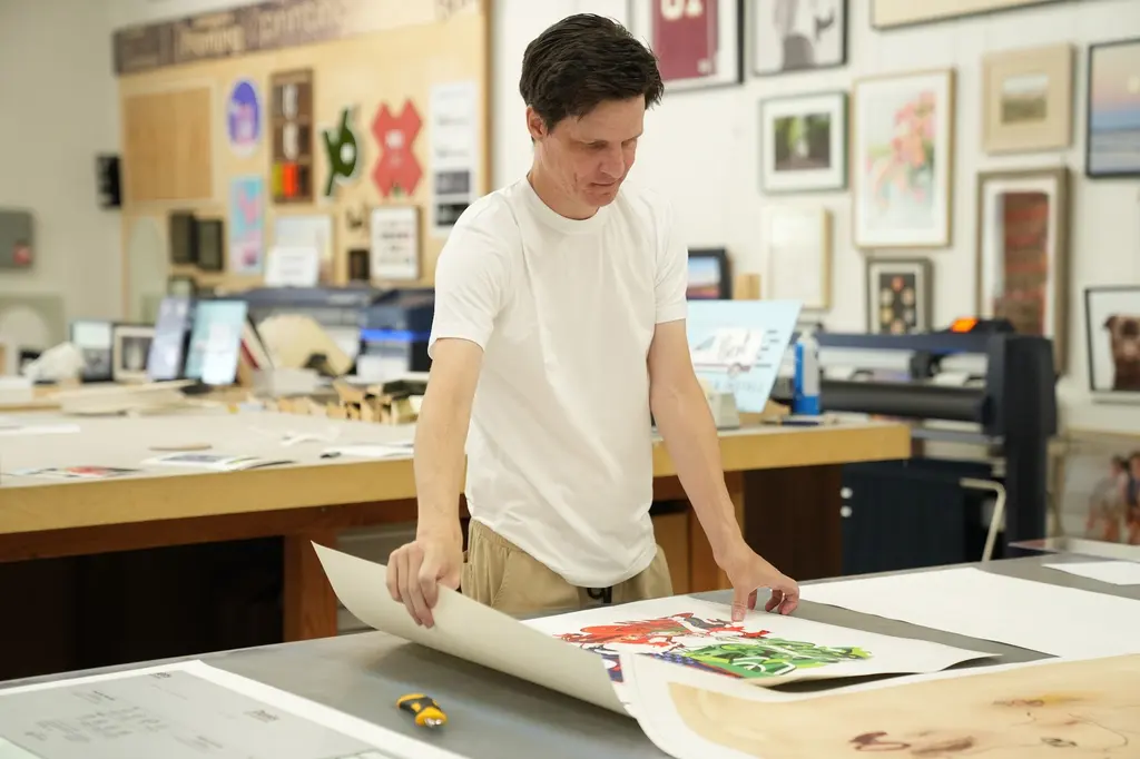 A team member laying a large print flat on the print-room table