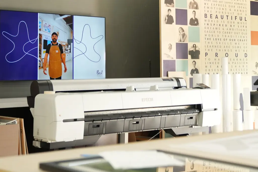 Best Framing’s white Epson large-format giclée printer in the print room, a Best Framing video playing on the screen above it