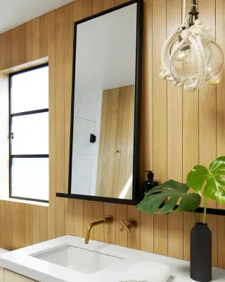 slim black framed mirror on vertical white oak panelling