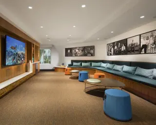 Framed black-and-white panoramas running the length of a clubhouse lounge above a teal banquette