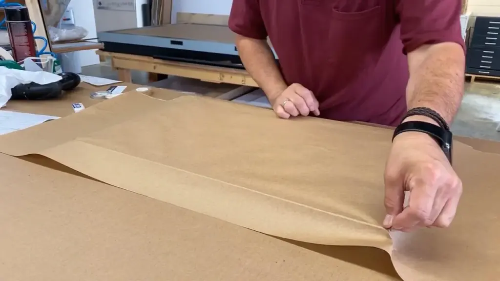 A sheet of kraft paper being folded down over a finished piece on the Best Framing packing bench