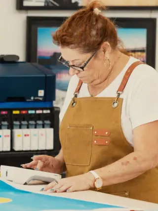 Stefanie at the print table, a large Epson printer and its row of ink cartridges behind her