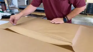 A finished piece being wrapped in kraft paper for shipping