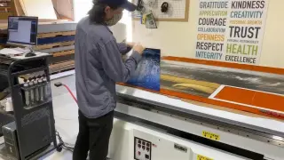 A printer loading artwork onto the flatbed in the print lab