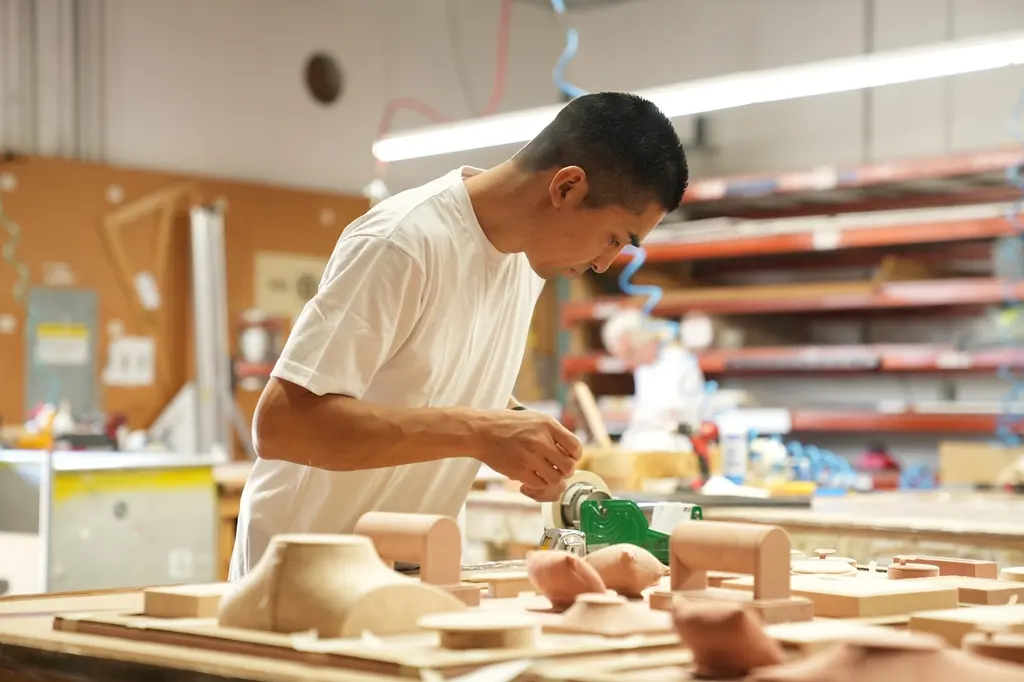 A woodworker shaping wooden blocks at the wood shop bench